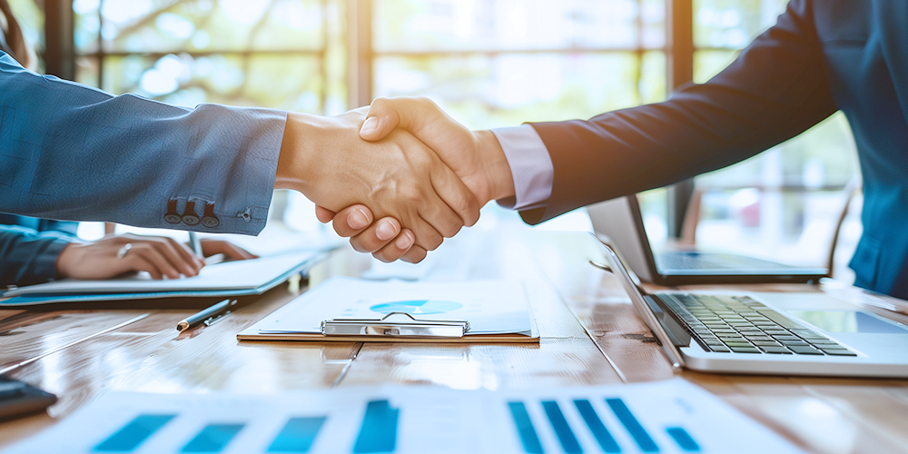 يتصافح المهنيون في مجال الأعمال على طاولة اجتماعات ، وتحيط به أجهزة الكمبيوتر المحمولة والوثائق ، ويرمزون إلى شراكات ناجحة في صناعة أدوات الطاقة.